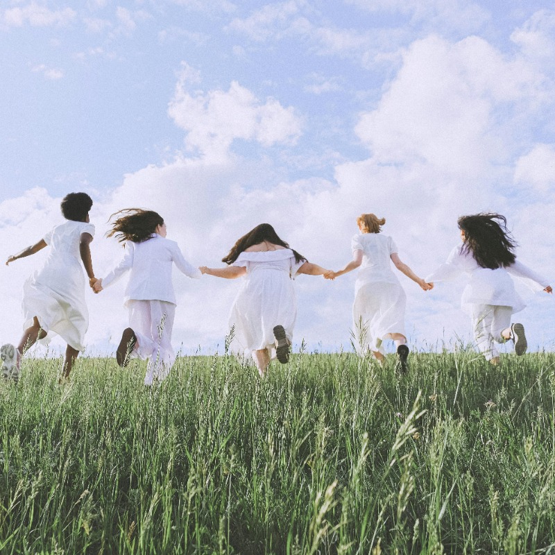 Group of women dressed in white running through a field