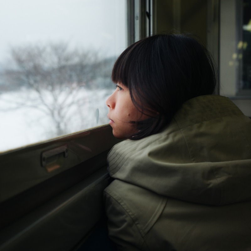 sad woman looks out window in winter