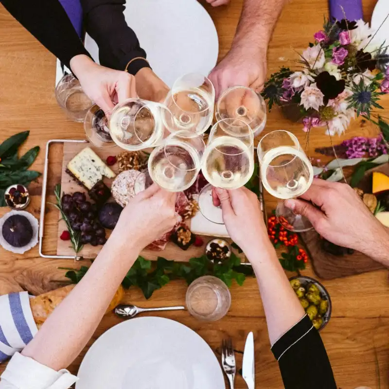 Birds eye view of a group of people cheersing their glasses together over the holiday dinner table